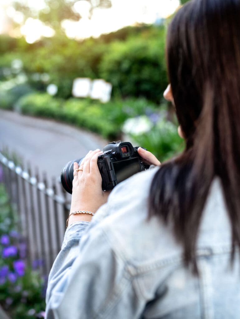 Orlando senior photography, Ann, of Petal and Stone Photography showing an over the shoulder shot of her holding a camera during her senior photo shoot sessions.