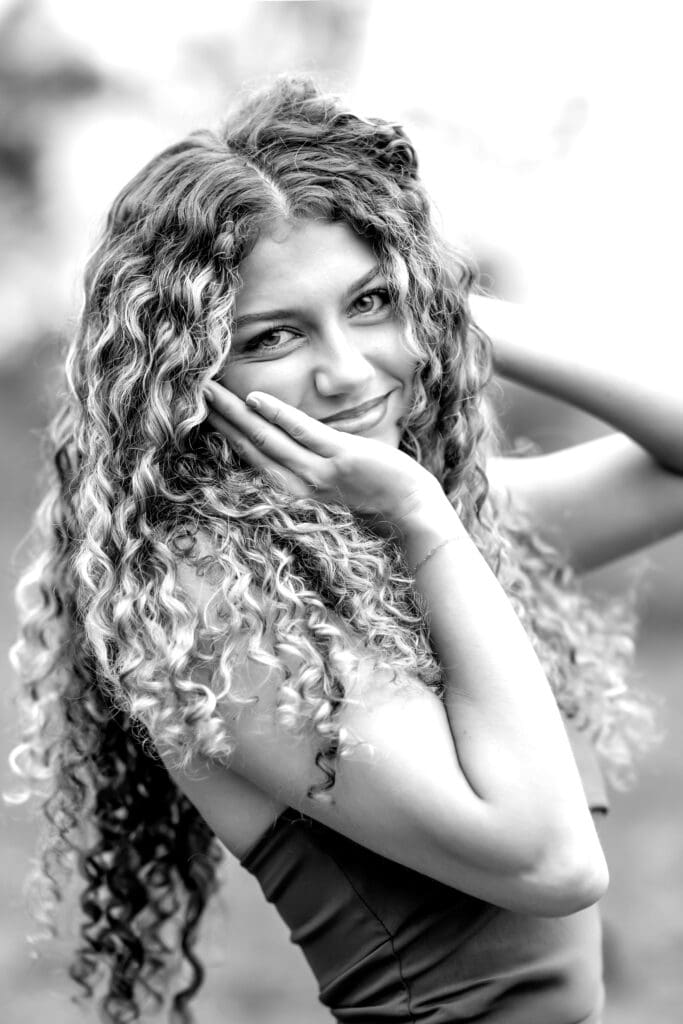 Senior girl in dramatic black and white close up with curly hair.